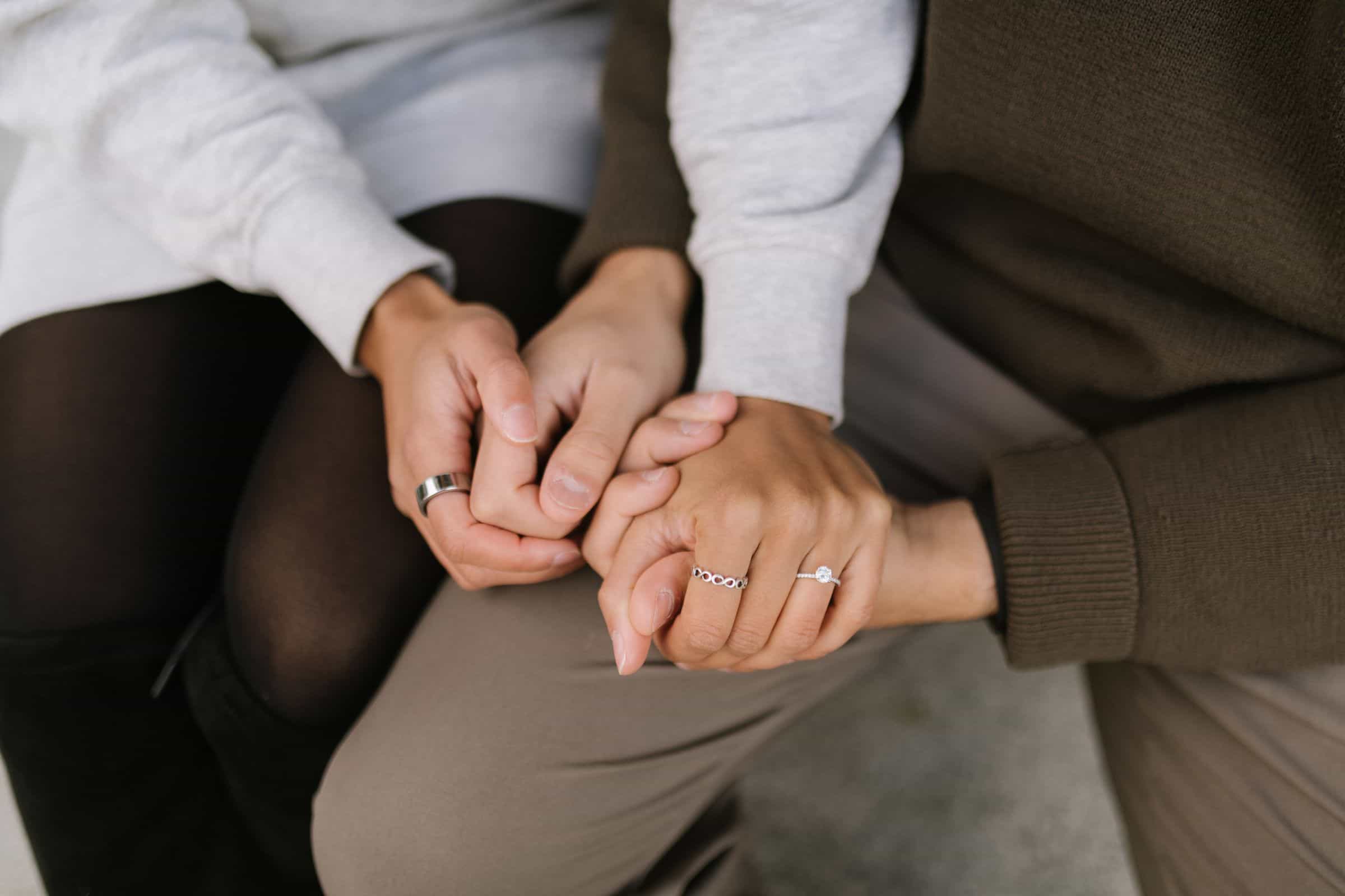 Two people holding hands, one wearing an engagement ring